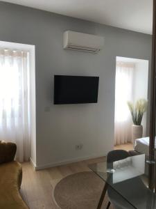 a living room with a television on a white wall at Aveiro Garden's Home in Aveiro