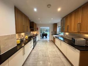 a large kitchen with wooden cabinets and a table at Castlebar in Great Singleton