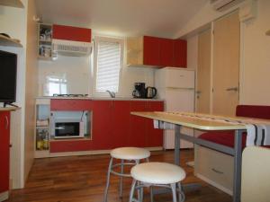 uma pequena cozinha com armários vermelhos e electrodomésticos brancos em Camping PINUS em Starigrad-Paklenica