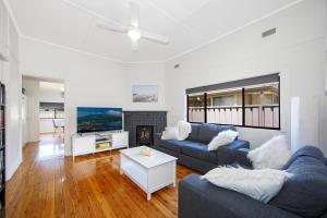 a living room with a blue couch and a fireplace at Large Cottage Near Ettalong Centre in Ettalong Beach