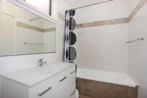 La salle de bains blanche est pourvue d'un lavabo et d'une baignoire. dans l'établissement Barralong Beach House, à Hawks Nest