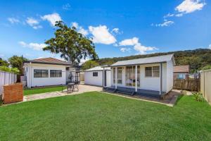 a small white house with a yard at Large Cottage Near Ettalong Centre in Ettalong Beach