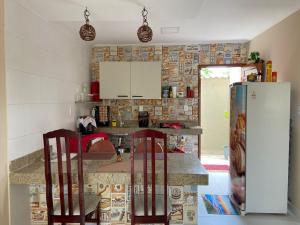 a kitchen with two chairs and a refrigerator at Cond Praia Linda - Gamboa do Morro de São Paulo in Cairu