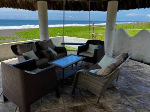 eine Terrasse mit Stühlen, einem Tisch und Meerblick in der Unterkunft Monterrico Casablanca in Chiquimulilla