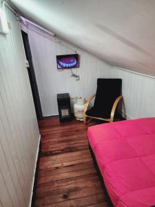 Habitación con cama y silla. en Hostal Capricho de Carlitos, en Valdivia