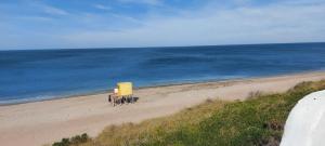 a yellow truck on a beach next to the ocean at Las Grutas Star in Las Grutas