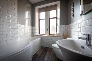 Baño blanco con bañera y lavamanos en Jardine Apartment @ Cairn Dhu House en Stornoway