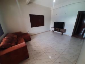 uma sala de estar com um sofá e uma televisão em L & C - Casa por Temporada em Macapá