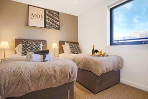 a bedroom with two beds and a window at Luxury Penthouse Apartment - Central MK - Pool Table, Balcony, Fast WiFi, Free Parking and Smart TVs with Sky TV and Netflix by Yoko Property in Milton Keynes