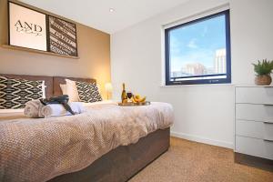 a bedroom with a large bed and a window at Luxury Penthouse Apartment - Central MK - Pool Table, Balcony, Fast WiFi, Free Parking and Smart TVs with Sky TV and Netflix by Yoko Property in Milton Keynes
