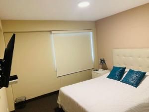 a bedroom with a large white bed with blue pillows at MLA apartments - Kennedy in Lima