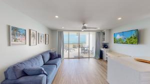 sala de estar con sofá azul y cocina en Soft, Sandy Beaches I Long Views from Premiere Over-sized Balcony!, en Marco Island