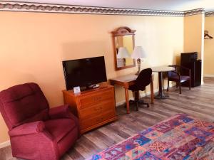 un soggiorno con TV, sedia e tavolo di Mountain inn & suites - Dunlap TN a Dunlap