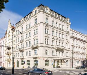 un grand bâtiment blanc avec des voitures garées devant lui dans l'établissement Best Western Hotel Moran, à Prague