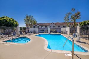 a swimming pool with chairs and a house at SureStay Plus Hotel by Best Western Upland - Ontario North in Upland