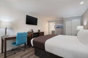 a bedroom with a bed and a desk with a blue chair at SureStay Plus Hotel by Best Western Upland - Ontario North in Upland