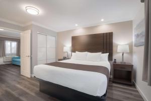 a bedroom with a large bed with a wooden headboard at SureStay Plus Hotel by Best Western Upland - Ontario North in Upland