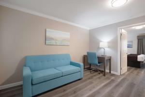 a living room with a blue couch and a desk at SureStay Plus Hotel by Best Western Upland - Ontario North in Upland