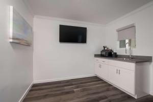 a kitchen with white cabinets and a flat screen tv at SureStay Plus Hotel by Best Western Upland - Ontario North in Upland