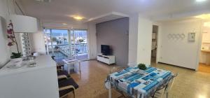 sala de estar con mesa y cocina con TV en Apartamento Bahia III, en Empuriabrava