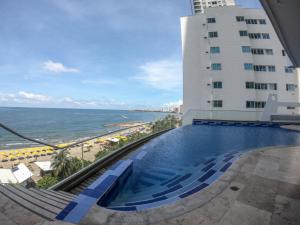 ein Pool neben einem Gebäude und dem Meer in der Unterkunft Beach front Apartament in Cartagena de Indias