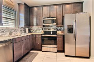 a kitchen with wooden cabinets and a stainless steel refrigerator at Family Tides Beach House in Port Aransas
