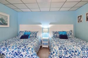two beds in a room with blue walls at On the Half Shell - Condo in Port Aransas