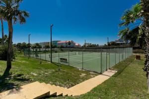 a tennis court in a park with palm trees at On the Half Shell - Condo in Port Aransas