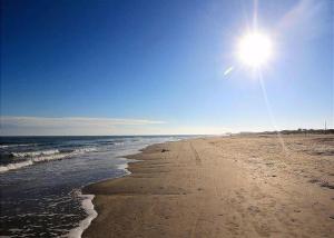 a sandy beach with the sun in the sky at On the Half Shell in Port Aransas