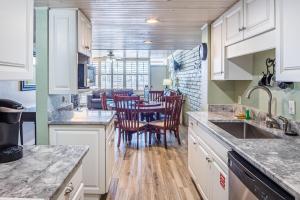 a kitchen with white cabinets and a table with chairs at Pearl- Marlin in Port Aransas