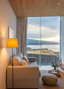 a living room with a couch and a large window at Sao Vicente Lodge - Atlantic Retreat in São Vicente Ferreira