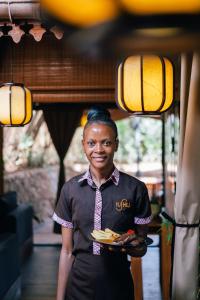 a woman is holding a plate of food at Yushili Hotel Kampala in Kampala