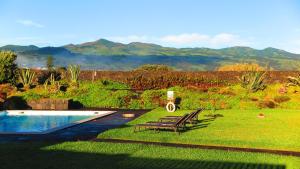 a backyard with a pool and two chairs and a table at Sao Vicente Lodge - Atlantic Retreat in São Vicente Ferreira