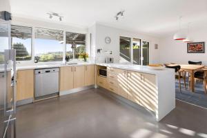 a kitchen with white counters and a dining room with a table at BYANDA MOUNT MARTHA in Mount Martha