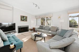 a living room with two couches and a tv at BYANDA MOUNT MARTHA in Mount Martha