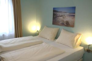 een slaapkamer met 2 bedden met witte lakens en kussens bij Hotel Yel in Ludwigshafen am Rhein
