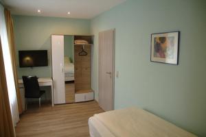 a bedroom with a bed and a desk with a television at Hotel Yel in Ludwigshafen am Rhein