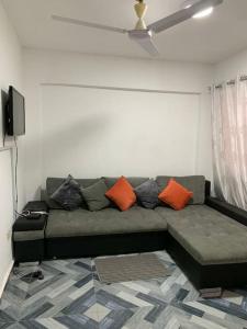 a living room with a green couch with orange pillows at Lovely 1-bedroom rental unit for short stays. in Tema