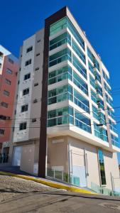 a tall white building with glass windows at APARTAMENTO BRISA do SOL 202 in Piratuba