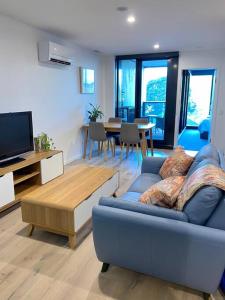 a living room with a blue couch and a tv at Central Canberra City apartment with study and full amenities including parking in Canberra