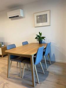 une table en bois avec des chaises et une plante en pot. dans l'établissement Central Canberra City apartment with study and full amenities including parking, à Canberra