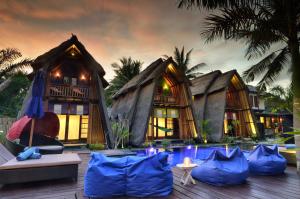 a resort with a pool in front of two huts at Kies Villas Lombok in Kuta Lombok