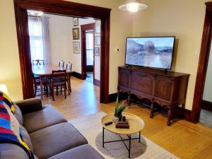 a living room with a couch and a flat screen tv at Dundurn Dwelling-Charming Century Home in Hamilton