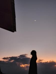 uma silhueta de uma pessoa em pé em frente a um pôr-do-sol em Uros Walysuma Titicaca Lodge em Puno