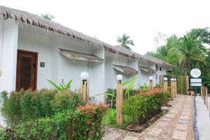 Ein weißes Gebäude mit einem Zaun davor. in der Unterkunft Phetrapoolvilla (เภตราพูลวิลล่า) in Surat Thani