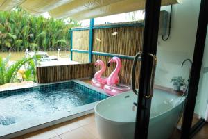 a bathroom with a tub and a pool with pink flamingos at Phetrapoolvilla (เภตราพูลวิลล่า) in Suratthani