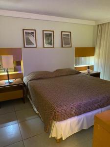 a bedroom with a large bed with two tables and two lamps at Varandas - Apartamentos in Natal
