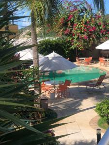 une piscine avec une table et un parasol dans l'établissement Varandas de PontaNegra - FLATS, à Natal 27 autres photos