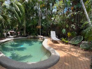 a pool with chairs and a chair in a yard at Dreamtime Travellers Rest in Cairns