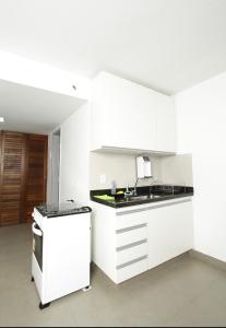 a white kitchen with a sink and a stove at Apartamento 1009 in Goiânia